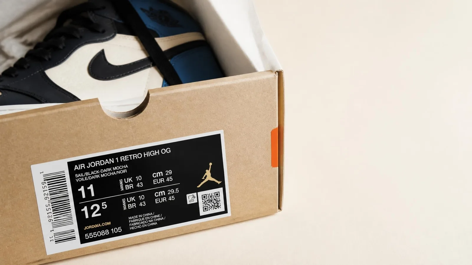 Close-up overhead view of an open sneaker shoebox with the box label in sharp focus and a sneaker partially visible inside, illustrating the process of checking physical release tier signals