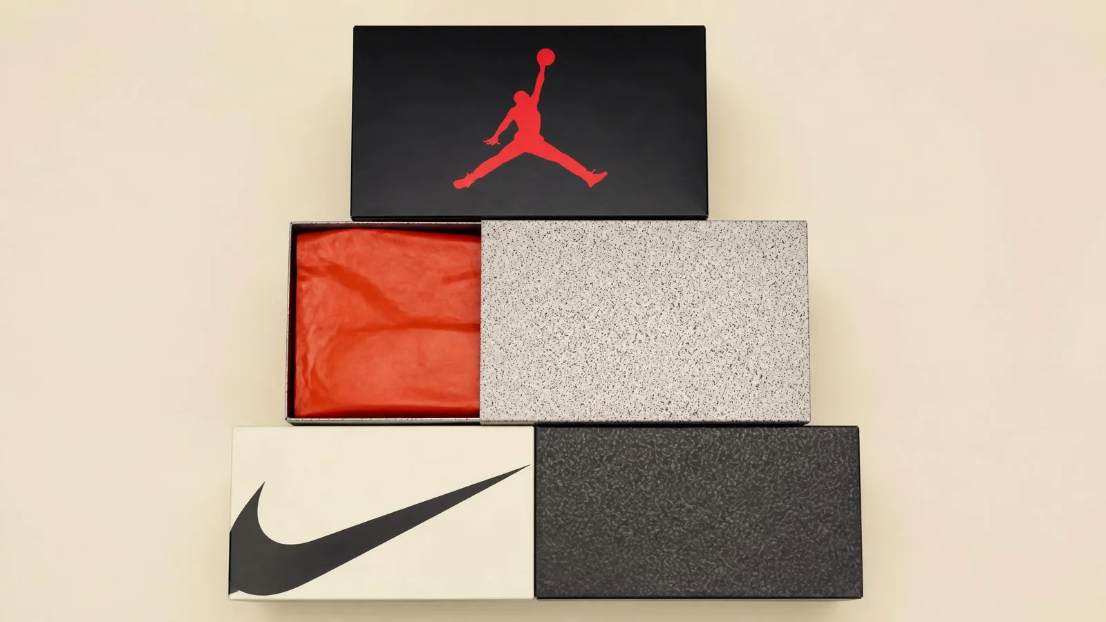 Overhead flat-lay of neatly stacked sneaker boxes on a warm cream surface, one box lid slightly open to reveal orange tissue paper inside, shot in clean studio lighting.