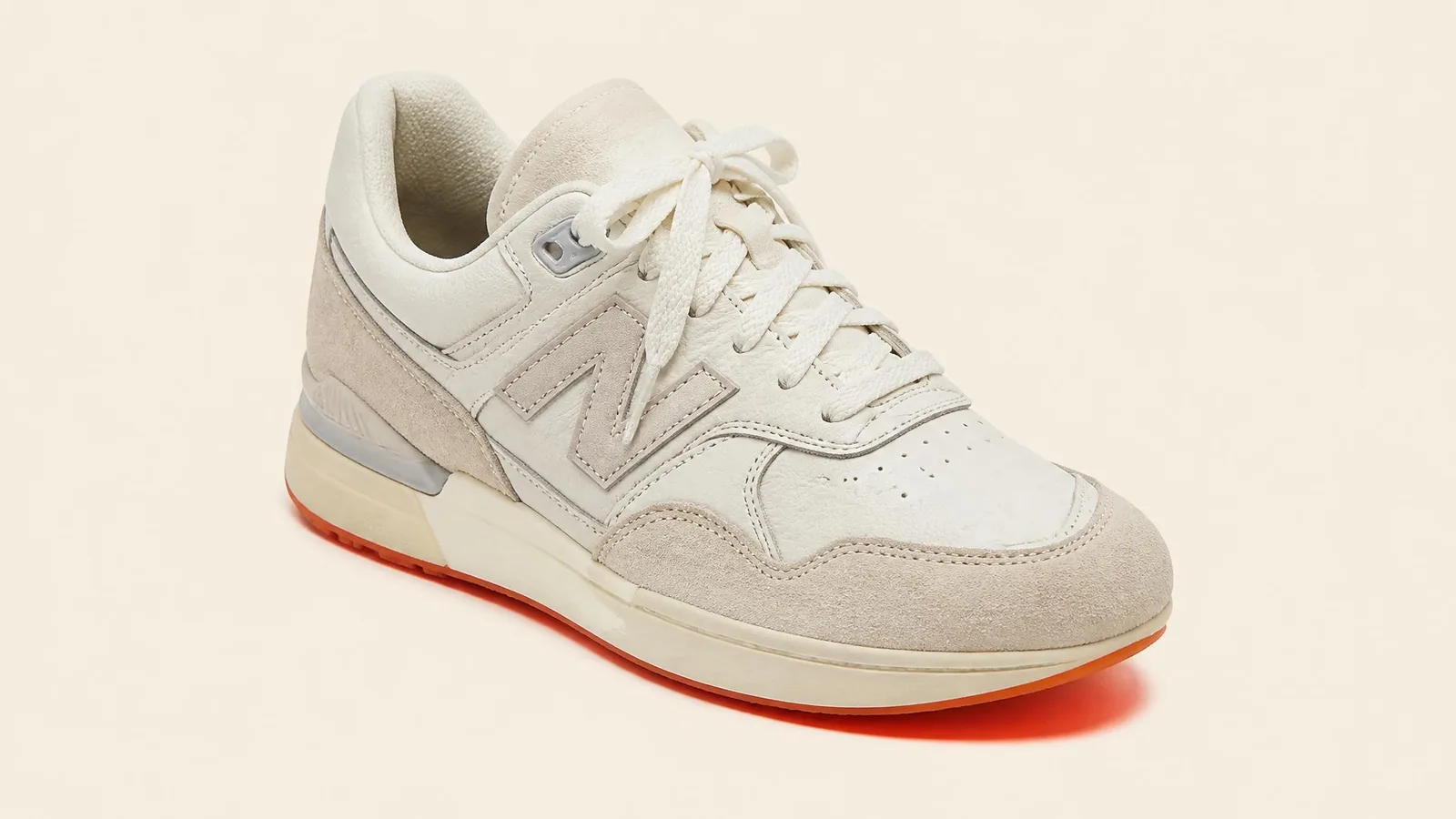 A three-quarter angle close-up of a single well-kept sneaker on a cream background with a subtle orange shadow beneath the sole, evoking the feeling of a final, considered decision.