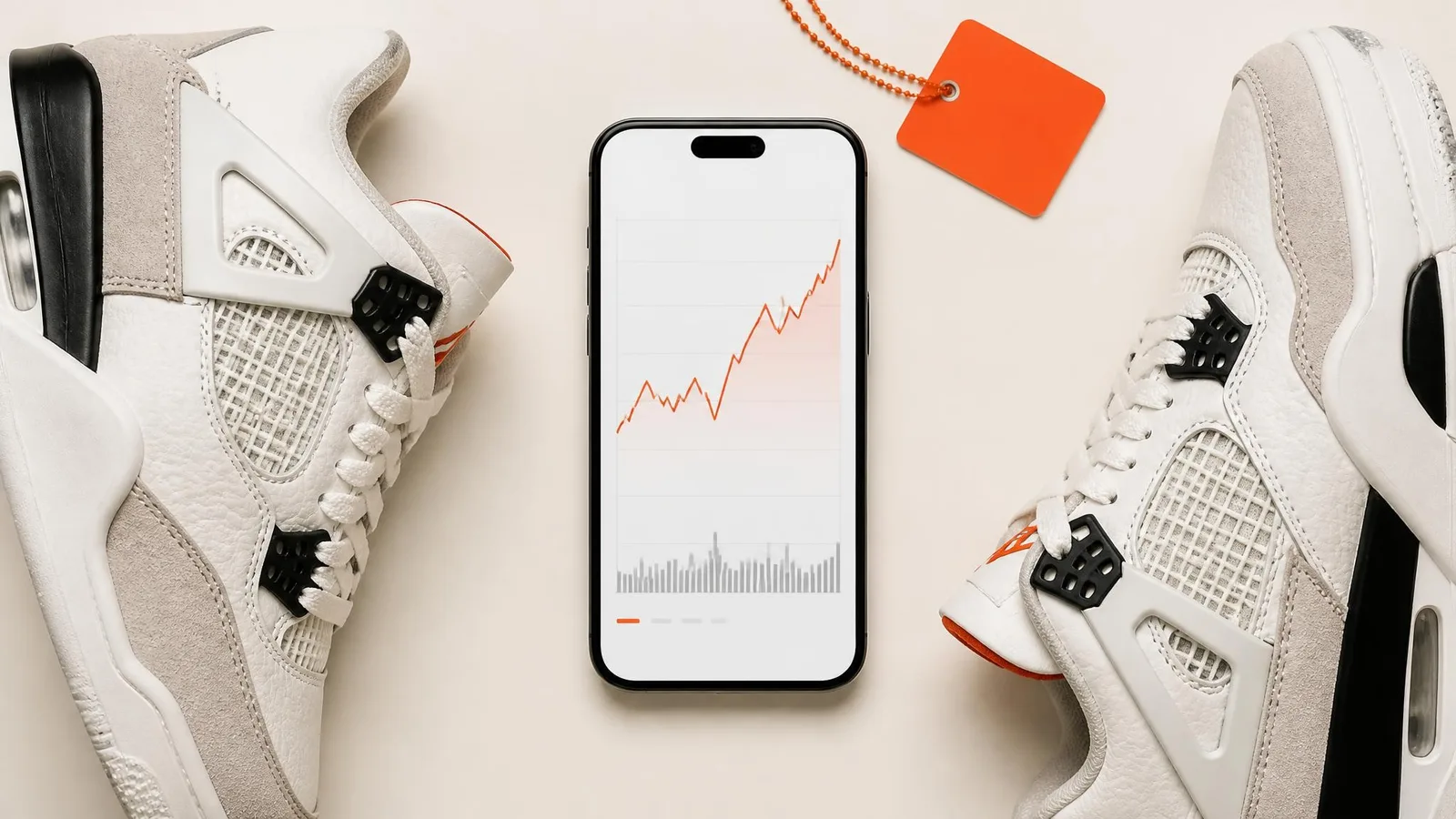 Overhead flat-lay of a smartphone showing a price chart resting between 2 sneakers on a warm off-white surface, representing a sneaker collector checking resale data to understand their collection's current market value.