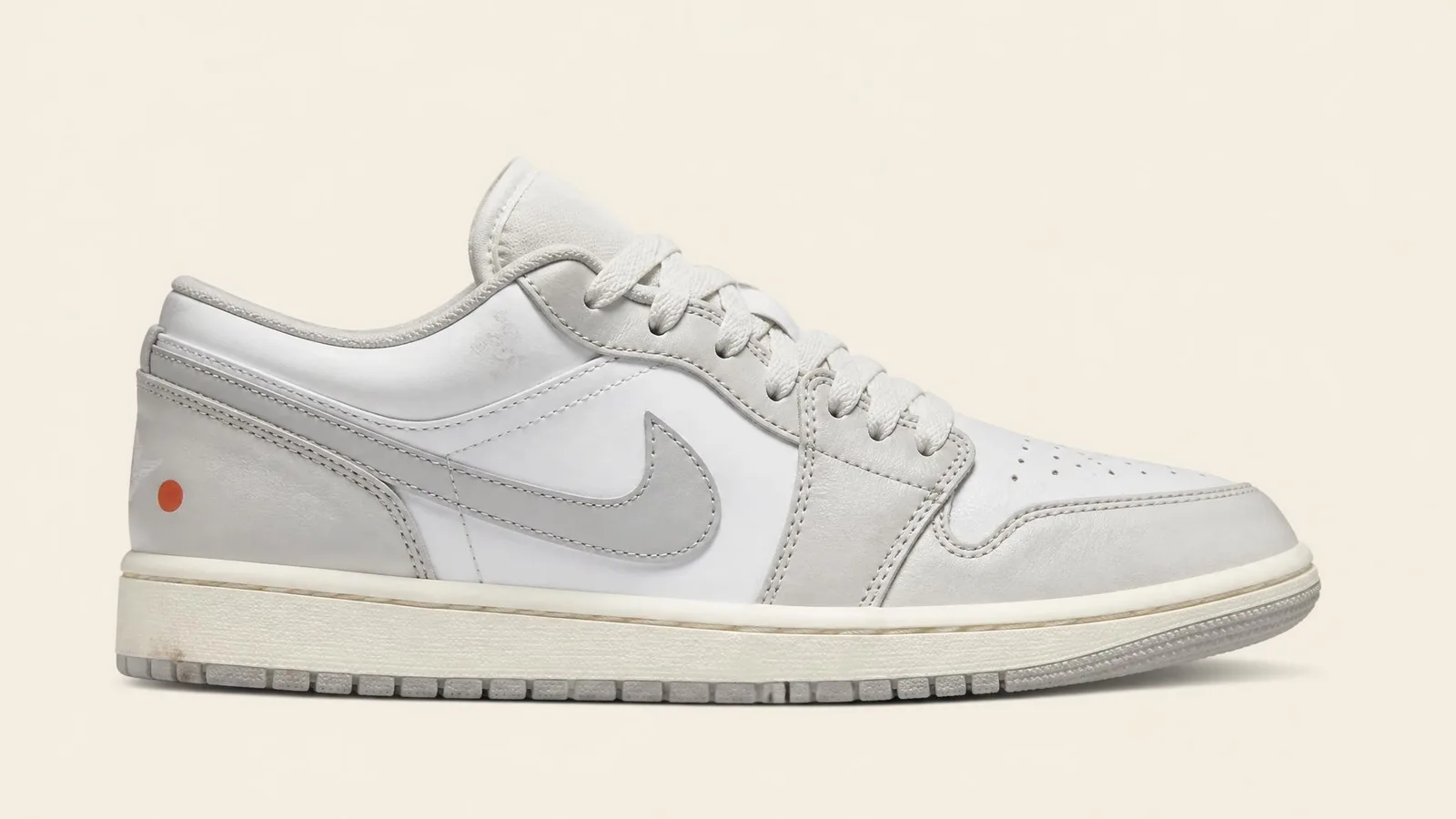 Single sneaker in side-profile showing subtle real-world wear including a faint toe-box crease, photographed in clean catalogue style against a warm cream background to illustrate honest condition recording.