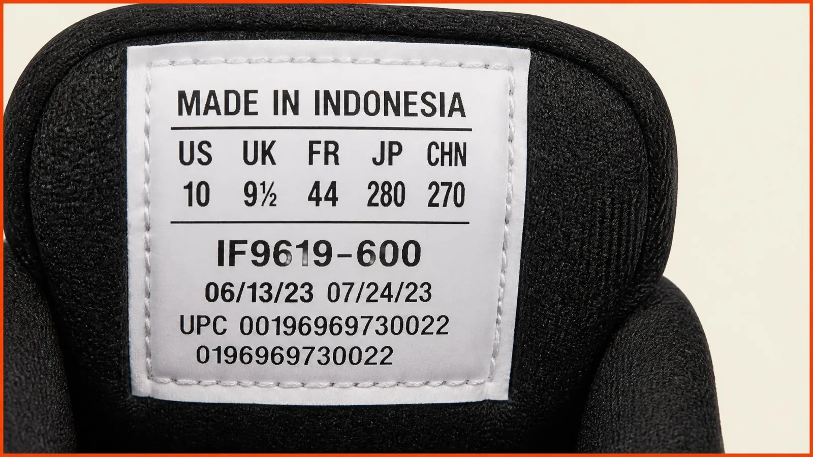 Close-up macro photograph of a sneaker tongue label with an alphanumeric style code string in sharp focus, stitching and label text visible around it.