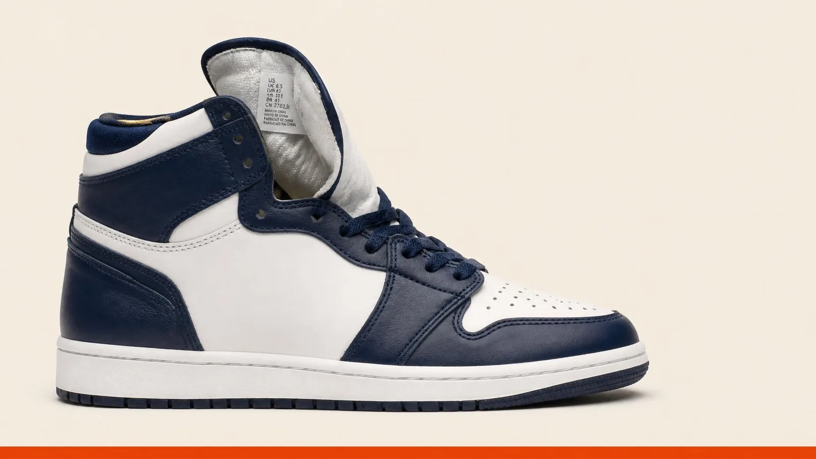 A sneaker shown in side profile with the tongue folded back to reveal the interior label, photographed in clean studio lighting against an off-white background.