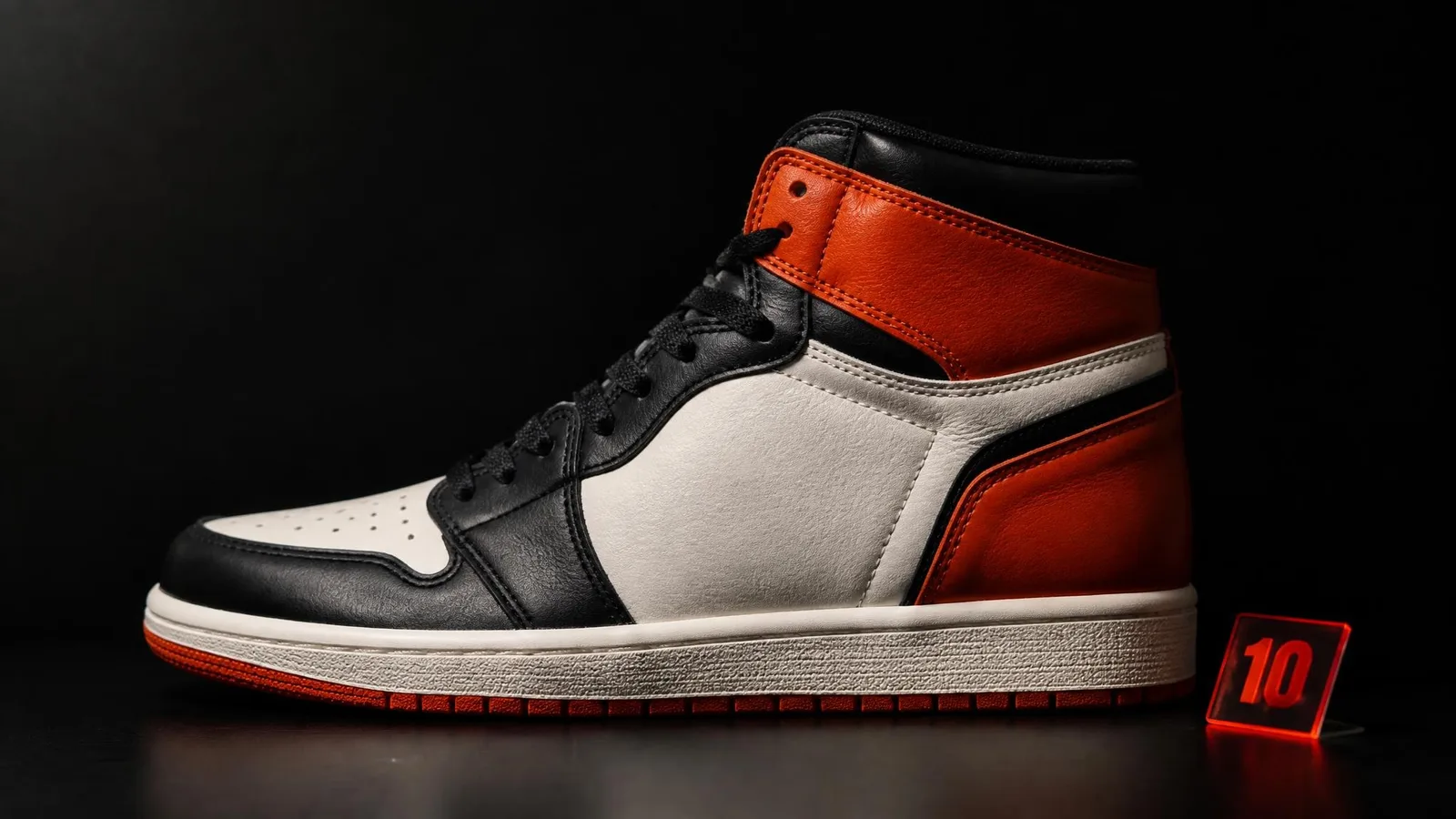 A single deadstock high-top sneaker in side-profile view with a size label placed beside it on a dark background, representing size-specific resale value dynamics across a model's full size run.