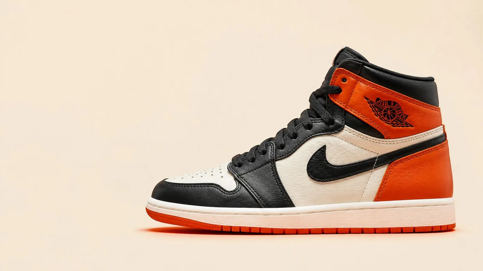 Dead-stock Air Jordan 1s photographed in clean side-profile against a warm cream background, showcasing the full silhouette with sharp detail on the leather upper and sole.